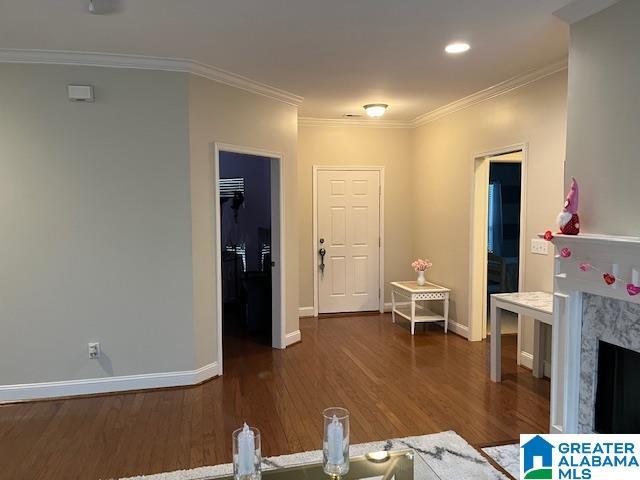 living area with crown molding, baseboards, dark wood-style flooring, and a high end fireplace