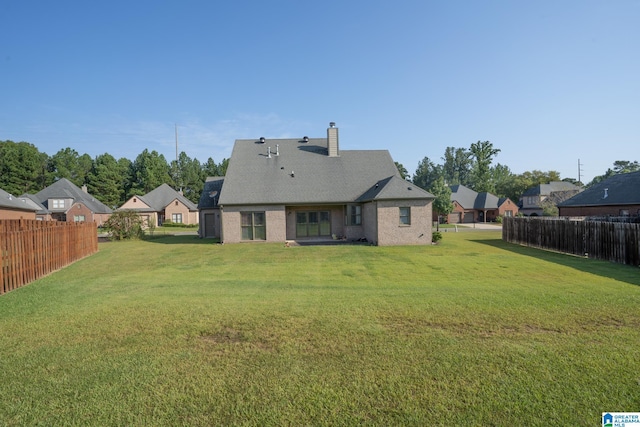 rear view of property with a chimney, fence, a lawn, and a residential view