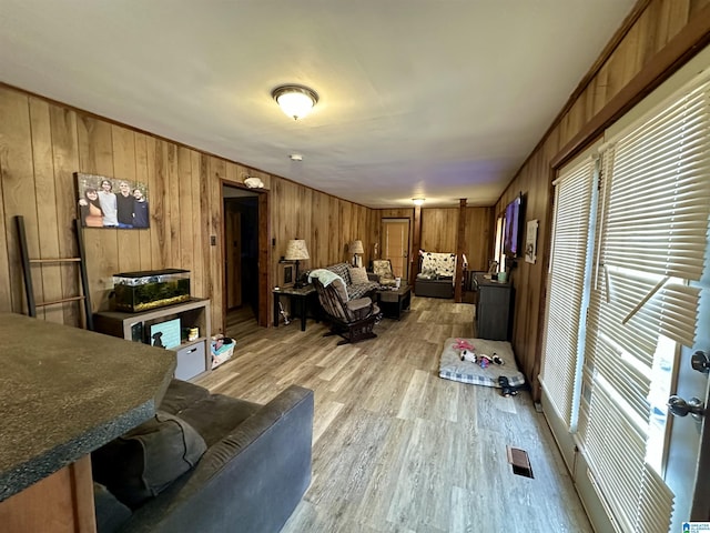 living room featuring wood walls, light wood-type flooring, and visible vents