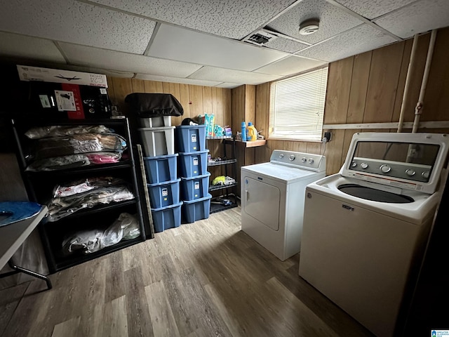 washroom with wood finished floors, wood walls, and separate washer and dryer