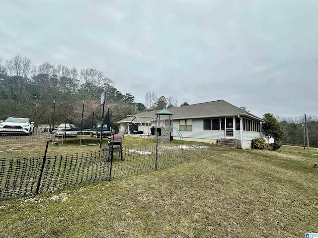 view of front of house featuring a front lawn, a trampoline, and fence