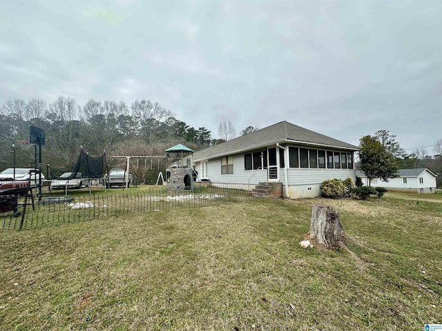 view of property exterior featuring crawl space, a trampoline, a lawn, and a playground