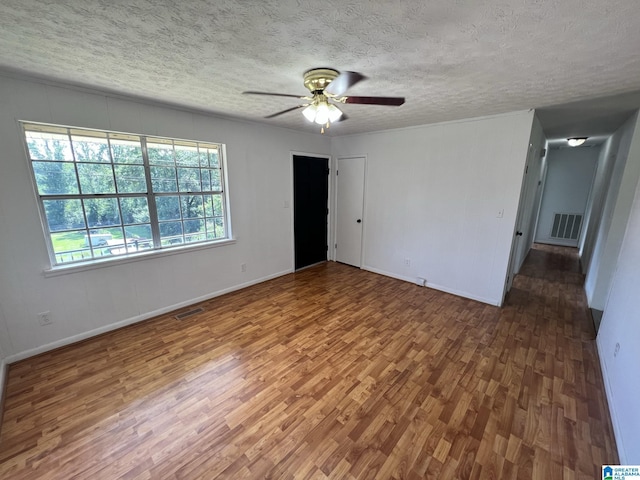 spare room with a ceiling fan, visible vents, a textured ceiling, and wood finished floors