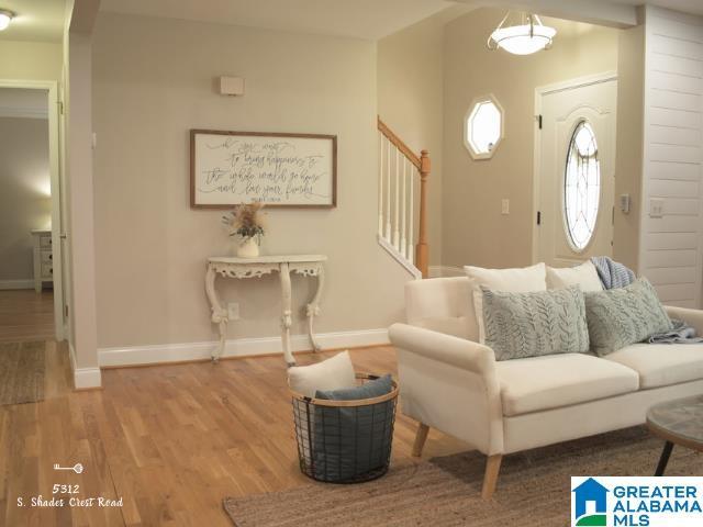 living area with light wood-type flooring, baseboards, and stairway