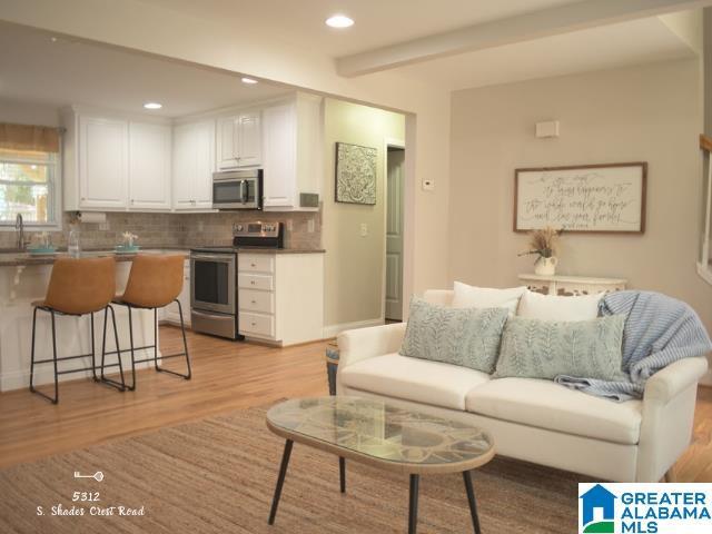 living room with light wood-style flooring, beamed ceiling, and recessed lighting