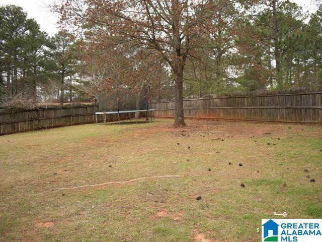 view of yard featuring a trampoline and a fenced backyard