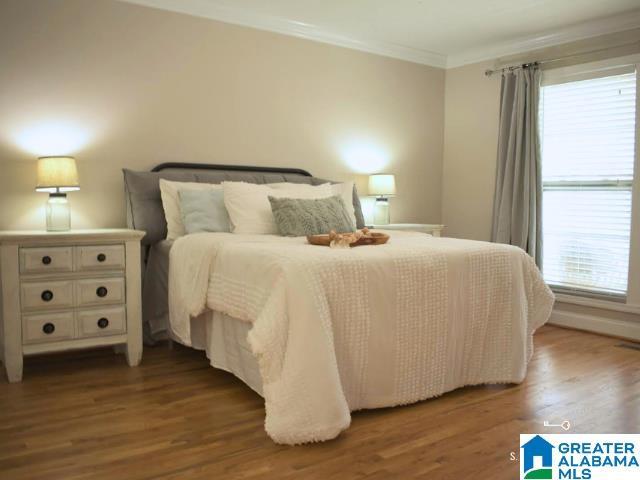 bedroom with dark wood finished floors and crown molding