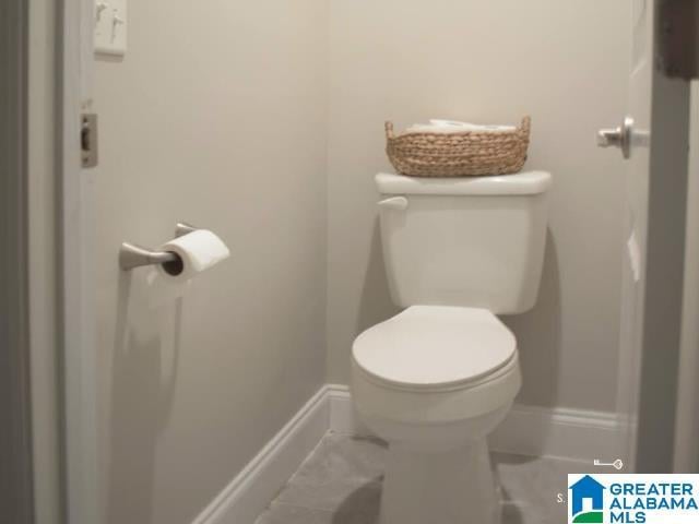 half bath featuring toilet and baseboards