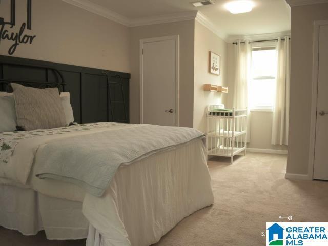 bedroom featuring baseboards, ornamental molding, visible vents, and light colored carpet