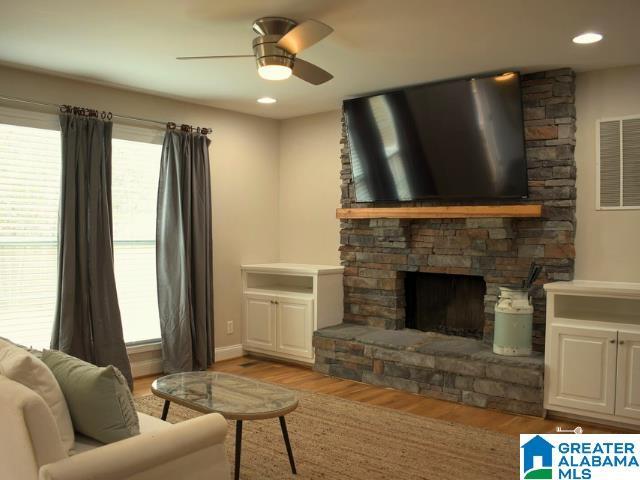 living area featuring recessed lighting, a fireplace, visible vents, a ceiling fan, and light wood-style floors