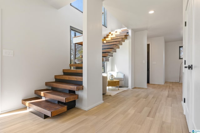 staircase with baseboards, wood finished floors, and recessed lighting