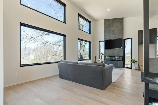 living room featuring recessed lighting, baseboards, a towering ceiling, and light wood finished floors