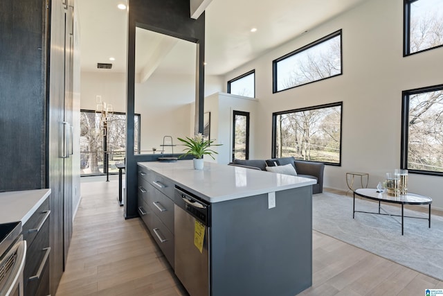 kitchen with stainless steel appliances, a center island, light wood-type flooring, and light countertops