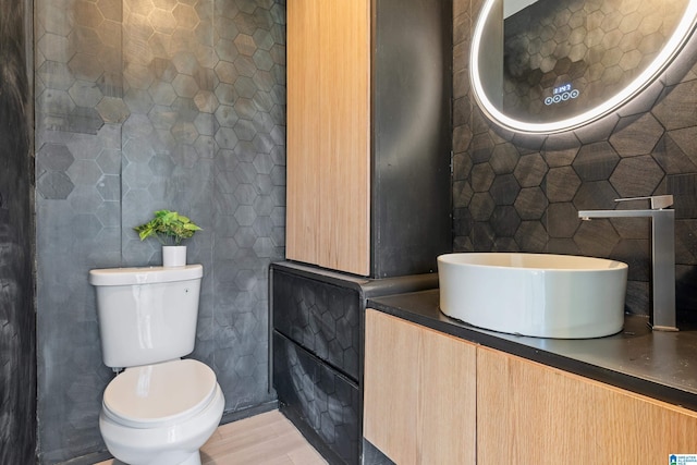 bathroom featuring toilet, tile walls, and vanity