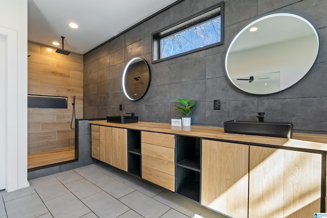 full bathroom featuring a sink, tile walls, tiled shower, tile patterned floors, and double vanity