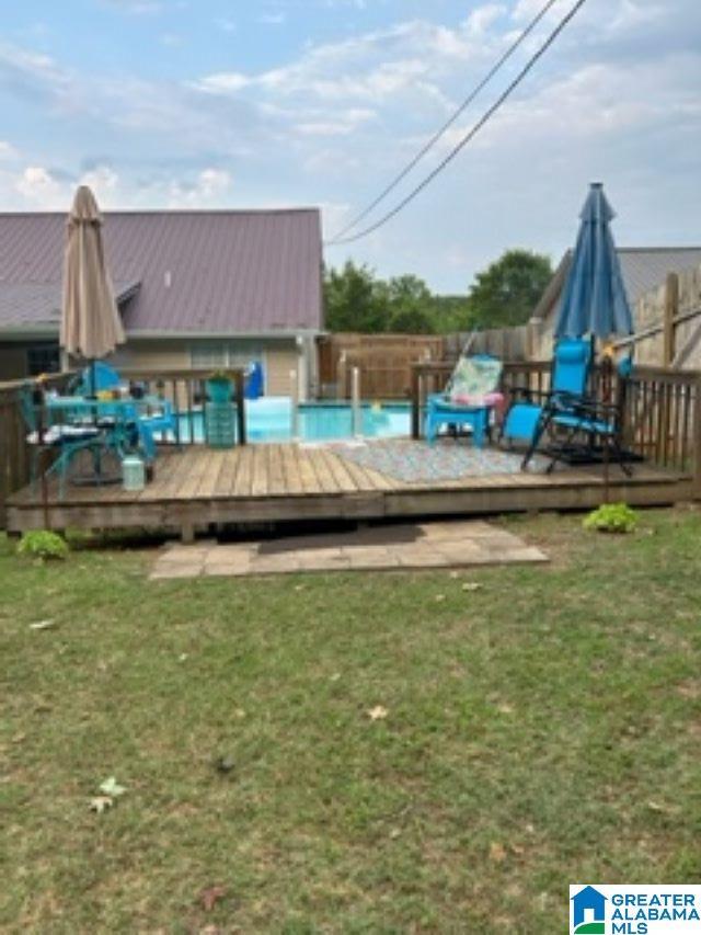 view of swimming pool featuring a fenced in pool, a yard, and a deck