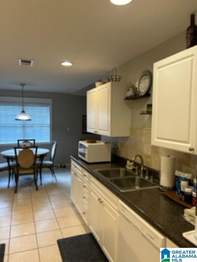 kitchen featuring white appliances, dark countertops, a sink, and white cabinetry