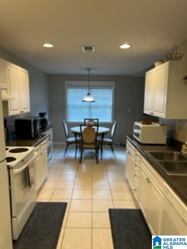 kitchen featuring white appliances, dark countertops, white cabinetry, and pendant lighting