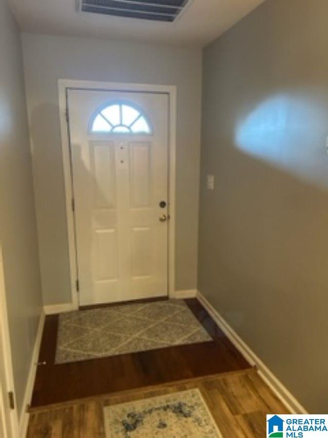 doorway featuring wood finished floors, visible vents, and baseboards