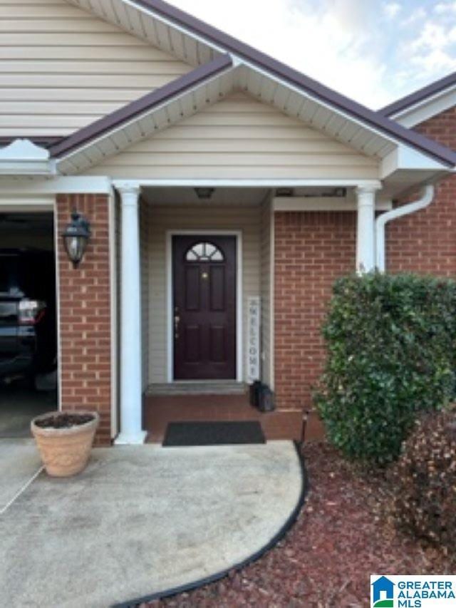 view of exterior entry featuring a garage and brick siding