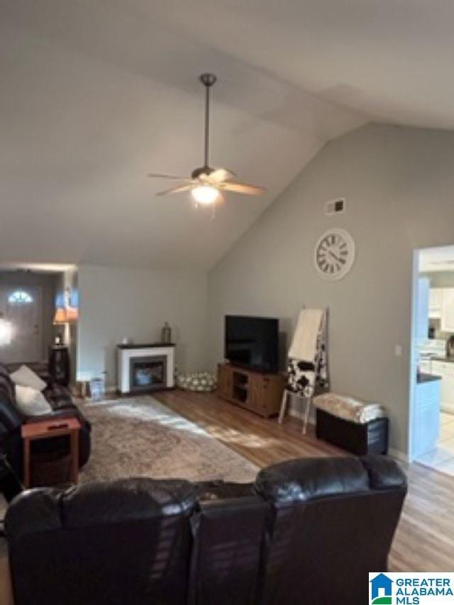 living area featuring ceiling fan, a fireplace, high vaulted ceiling, and wood finished floors