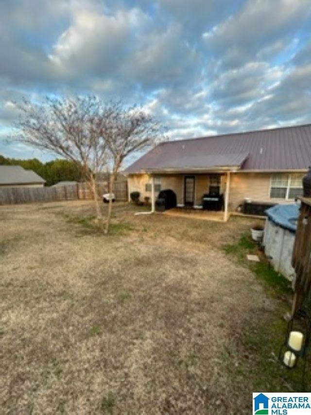 back of house with metal roof and fence