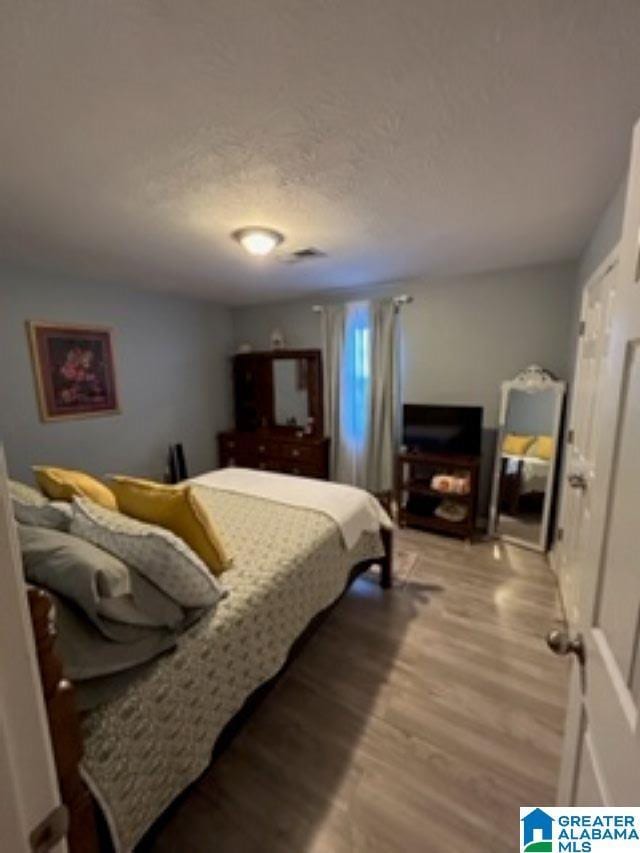 bedroom with a textured ceiling and light wood-style floors