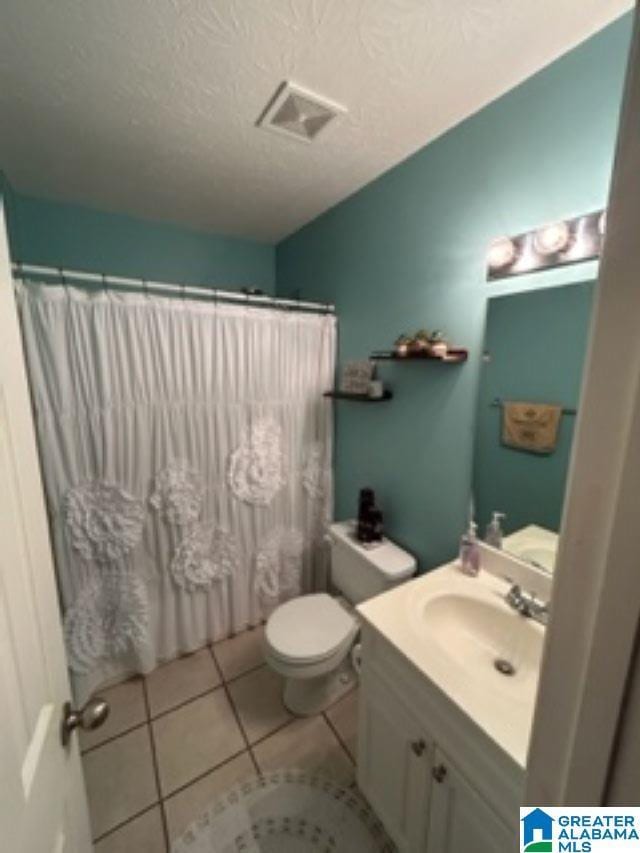 full bathroom with a textured ceiling, tile patterned flooring, toilet, visible vents, and vanity