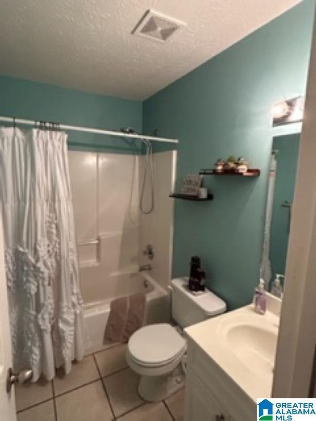 full bathroom featuring a textured ceiling, vanity, visible vents, tile patterned floors, and shower / bath combo with shower curtain