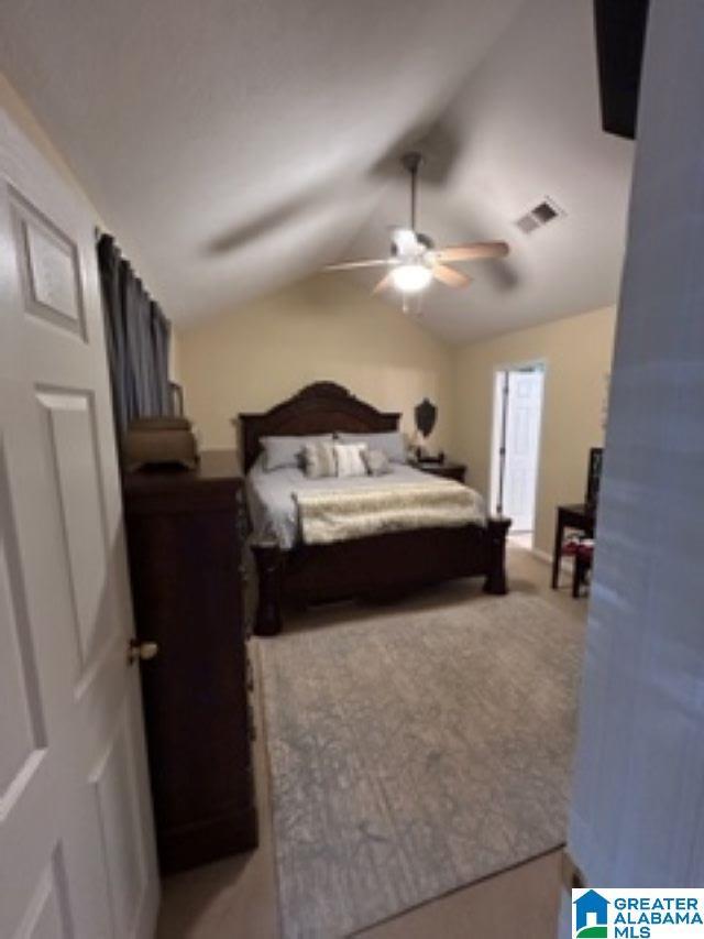 bedroom featuring lofted ceiling, a ceiling fan, visible vents, and light colored carpet