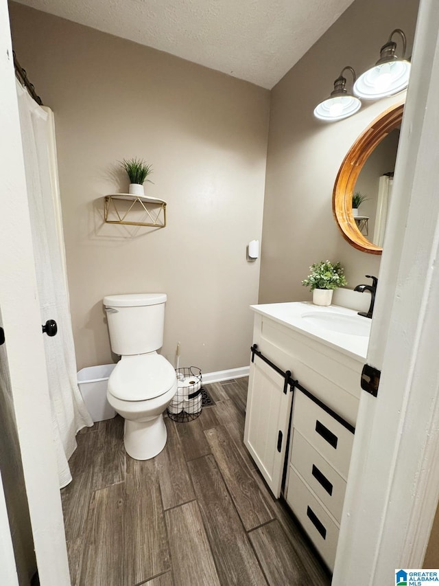 full bath with baseboards, toilet, wood finished floors, a textured ceiling, and vanity