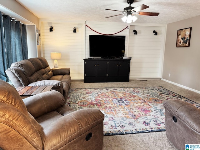 carpeted living room featuring wood walls, ceiling fan, a textured ceiling, and baseboards