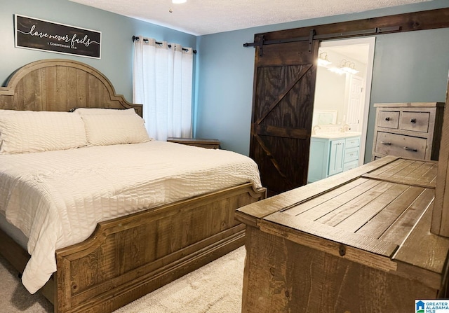 bedroom featuring a barn door, a textured ceiling, and ensuite bathroom