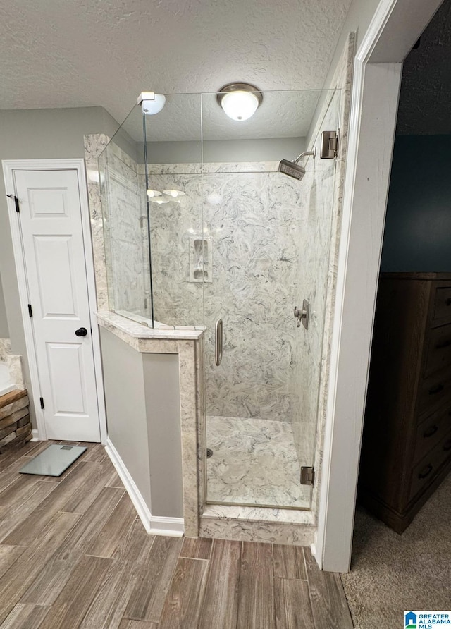 full bath with a textured ceiling, a stall shower, and wood tiled floor