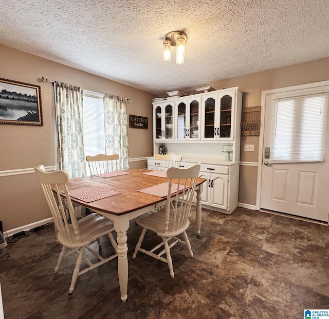 dining space featuring baseboards and a textured ceiling