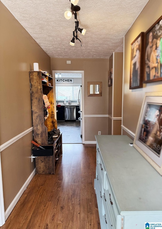 corridor featuring dark wood-style floors, a textured ceiling, and baseboards