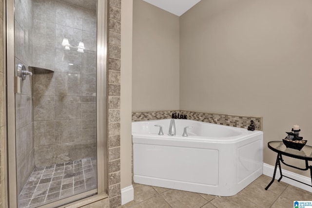 full bathroom featuring a stall shower, a garden tub, baseboards, and tile patterned floors