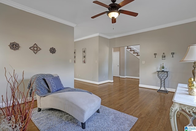 sitting room featuring baseboards, a ceiling fan, dark wood-type flooring, stairs, and crown molding