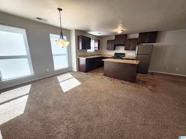 kitchen featuring a kitchen island, light countertops, black electric range, freestanding refrigerator, and pendant lighting