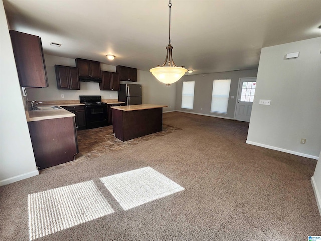 kitchen featuring a center island, light countertops, open floor plan, a sink, and black appliances