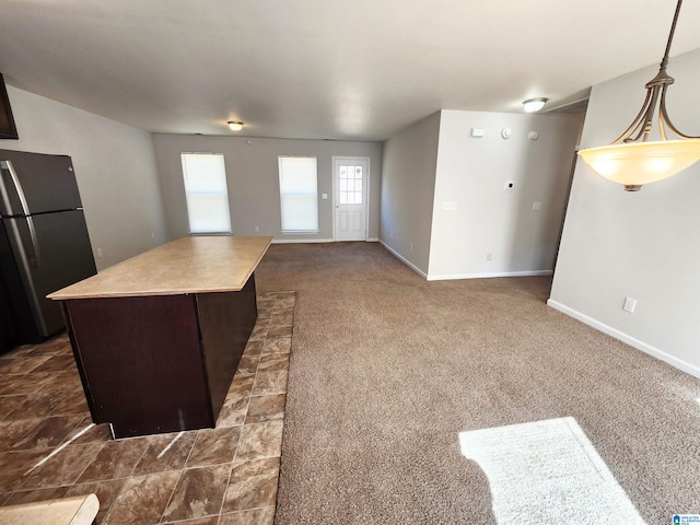 kitchen with open floor plan, freestanding refrigerator, a center island, dark carpet, and decorative light fixtures