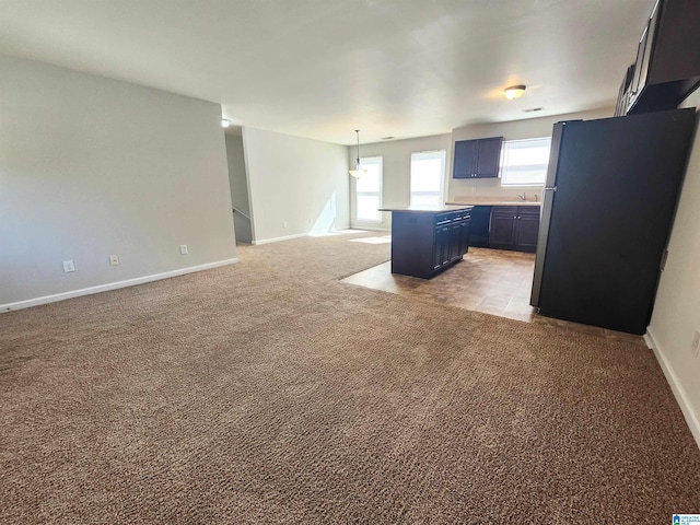 kitchen with a center island, light countertops, freestanding refrigerator, open floor plan, and light carpet