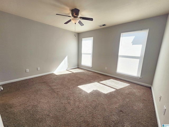 carpeted empty room with visible vents, ceiling fan, and baseboards