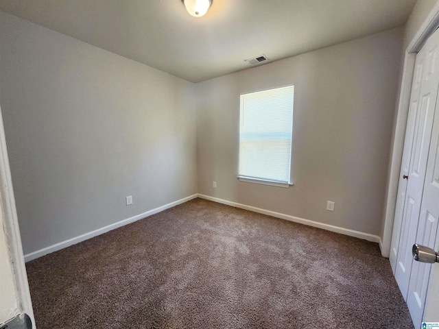 unfurnished bedroom featuring dark colored carpet, a closet, visible vents, and baseboards