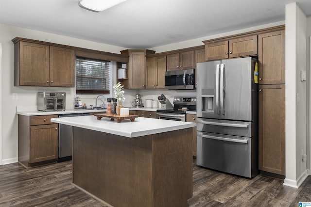 kitchen with dark wood-style floors, light countertops, appliances with stainless steel finishes, and a center island