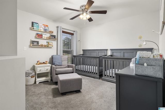 carpeted bedroom with ceiling fan and a crib