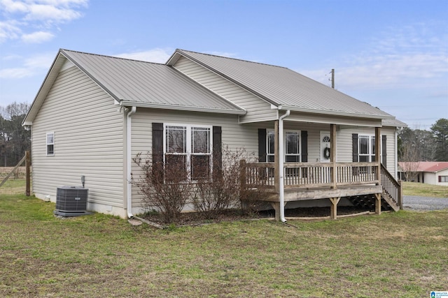 view of front of property with covered porch, central AC, a front lawn, and metal roof