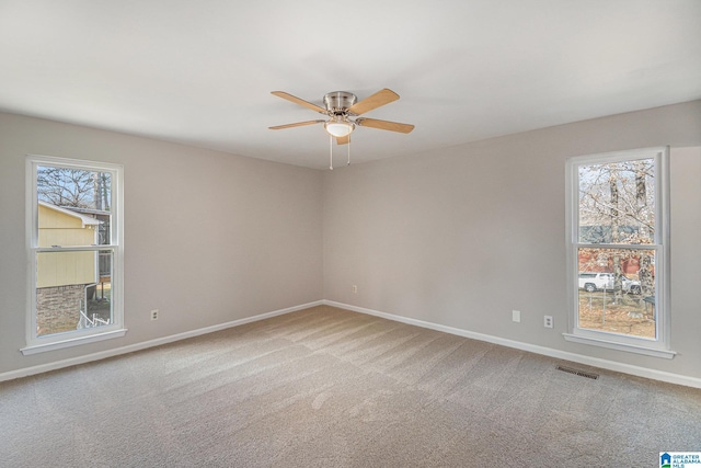 carpeted empty room featuring baseboards, visible vents, and a ceiling fan