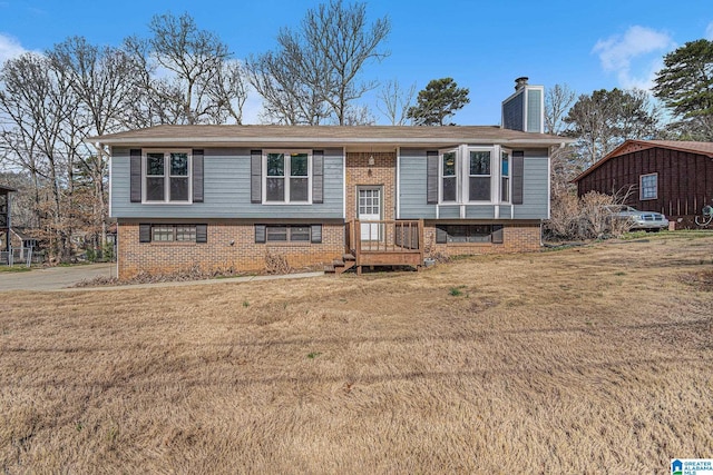 raised ranch featuring a front yard, brick siding, and a chimney