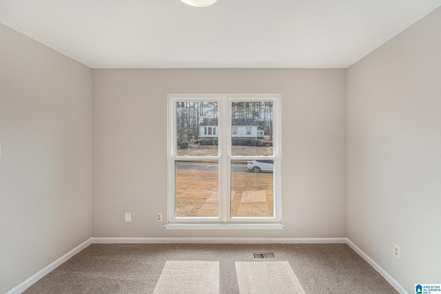 spare room featuring baseboards, visible vents, and carpet flooring